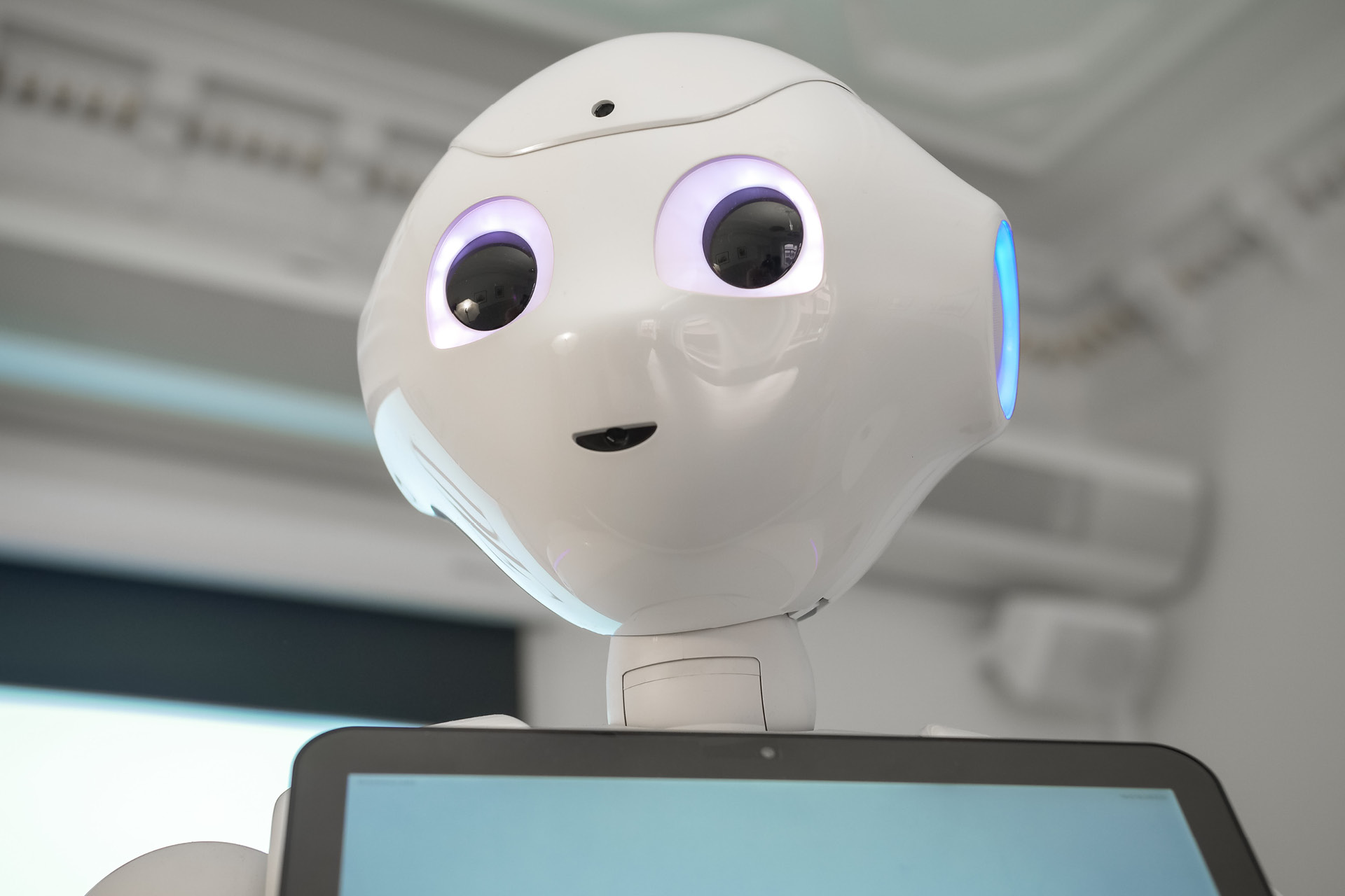Roboten Pepper. En vit robot som håller i en skärm.
